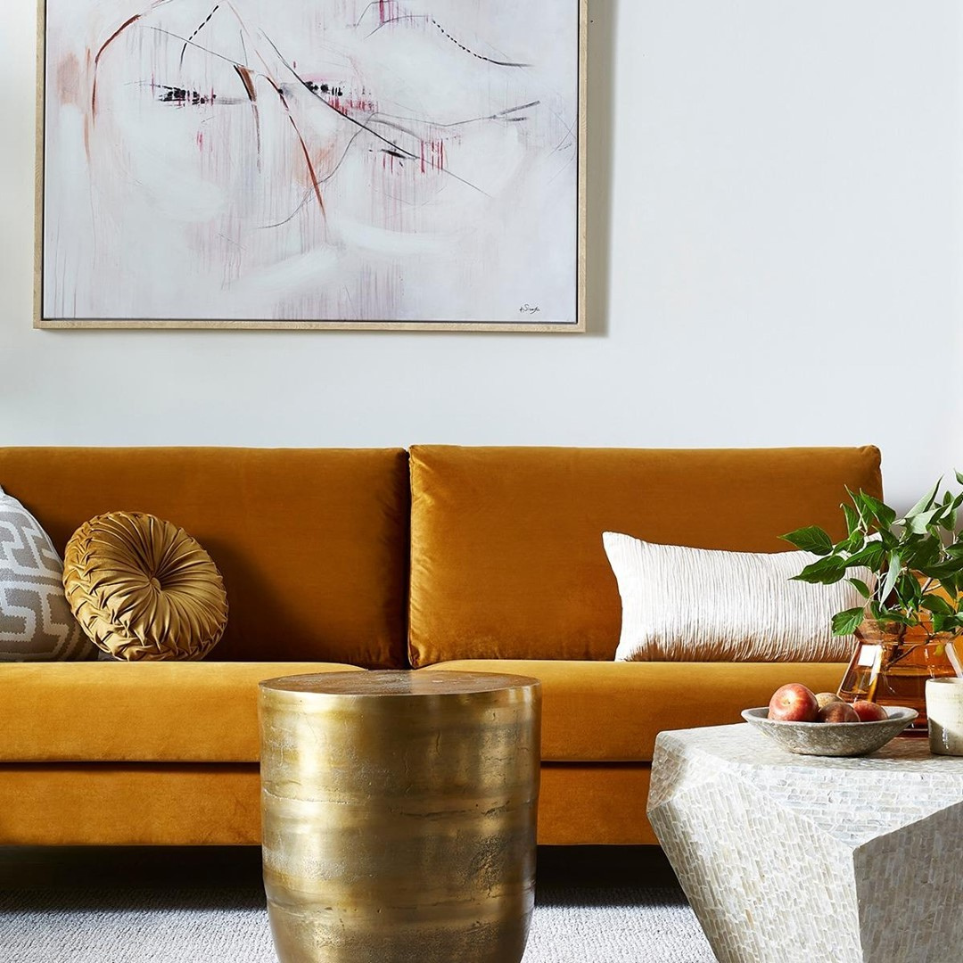 Orange velvet couch with a gold round coffee table